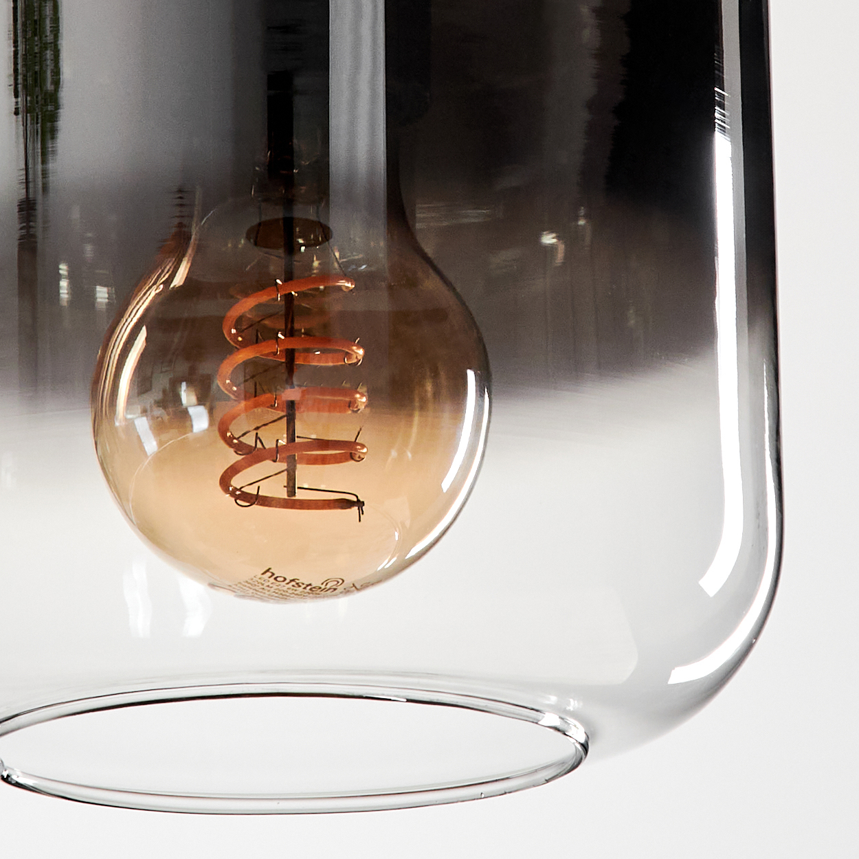 Nahaufnahme einer Pendelleuchte mit Spiralfaden in einem Glasschirm.