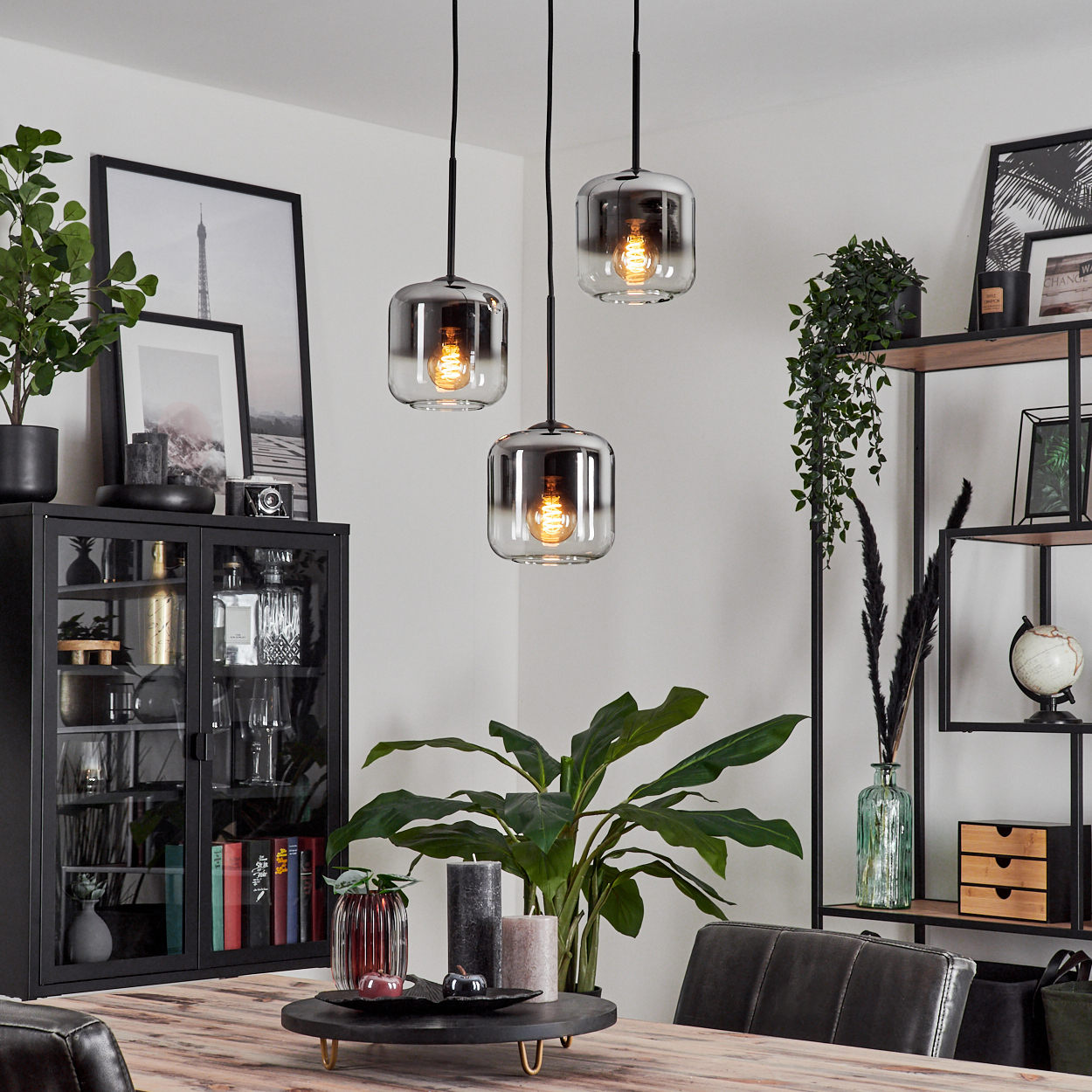 Ein Esszimmer mit Holztisch, drei Pendelleuchten und dekorativen Elementen.