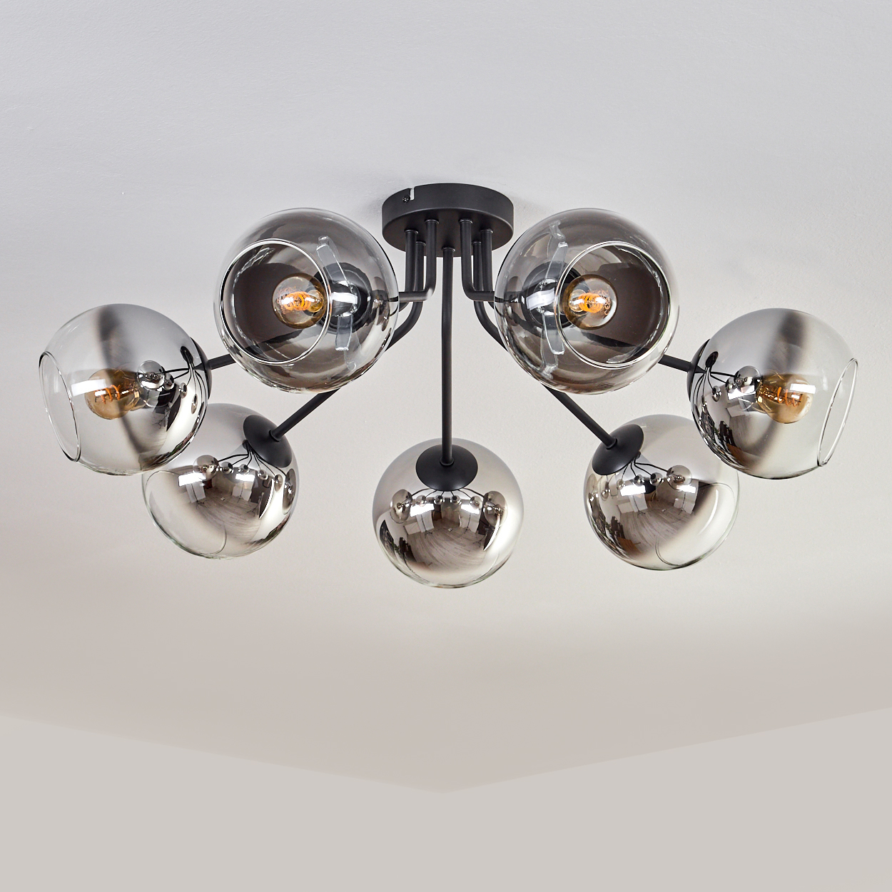 Deckenlampe mit sechs verspiegelten kugelförmigen Schirmen, beleuchtet von warmem Licht in einem Zuhause.