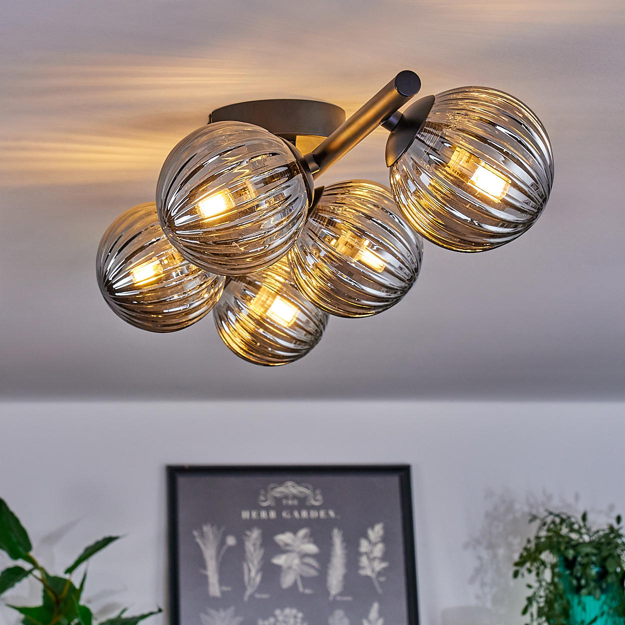 Deckenlampe mit fünf verspiegelten kugelförmigen Schirmen, beleuchtet von warmem Licht.