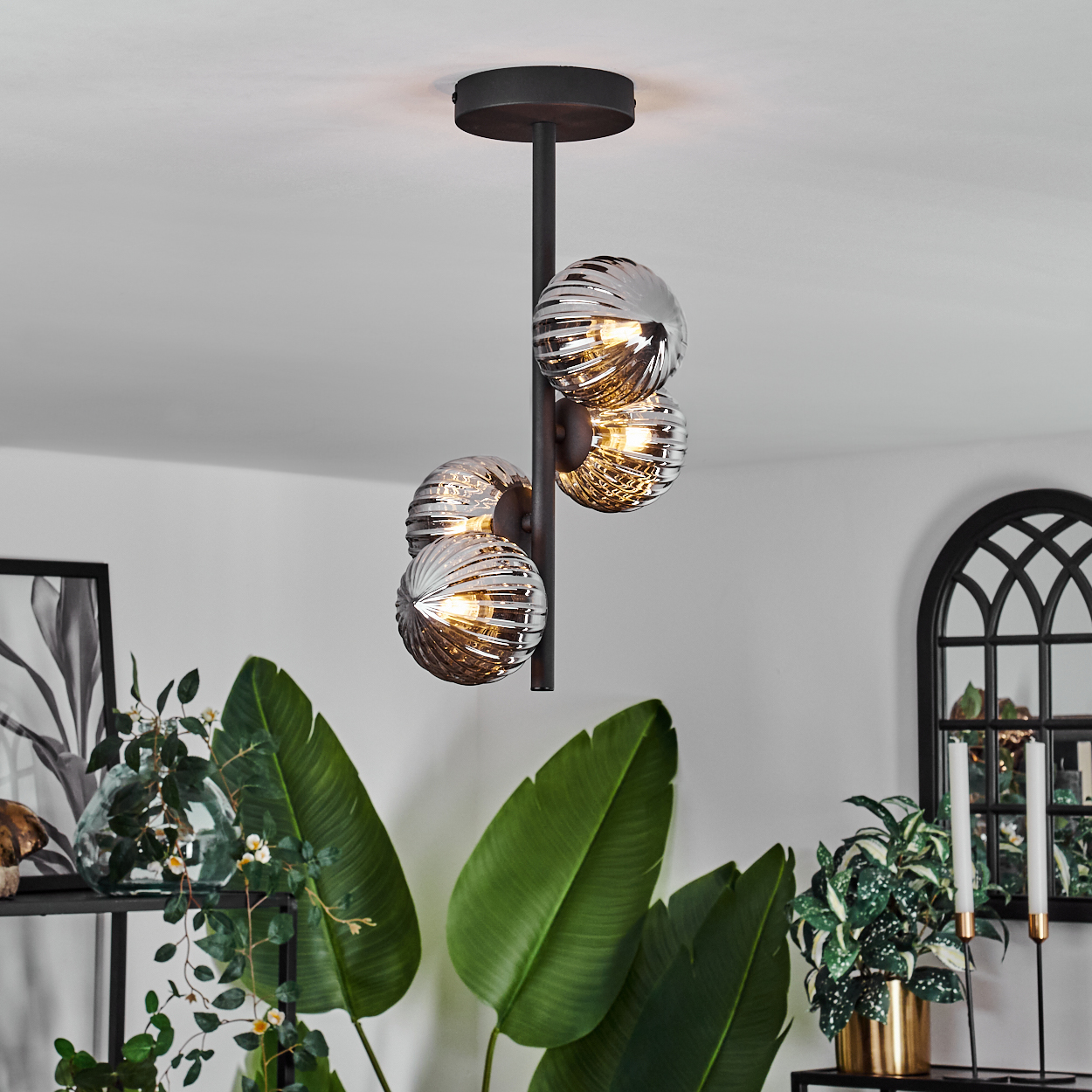 Eine Lampe mit vier verspiegelten Kugeln. Die Lampe hat einen schwarzen Stiel und ist vor einem weißen Hintergrund montiert.