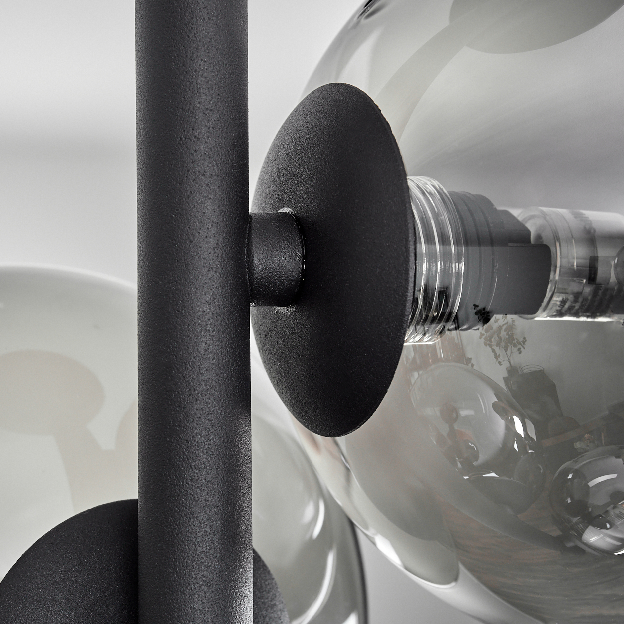 Nahaufnahme eines schwarzen Metallteils, das eine klare Glaskugel mit einer Glühbirne im Inneren hält.