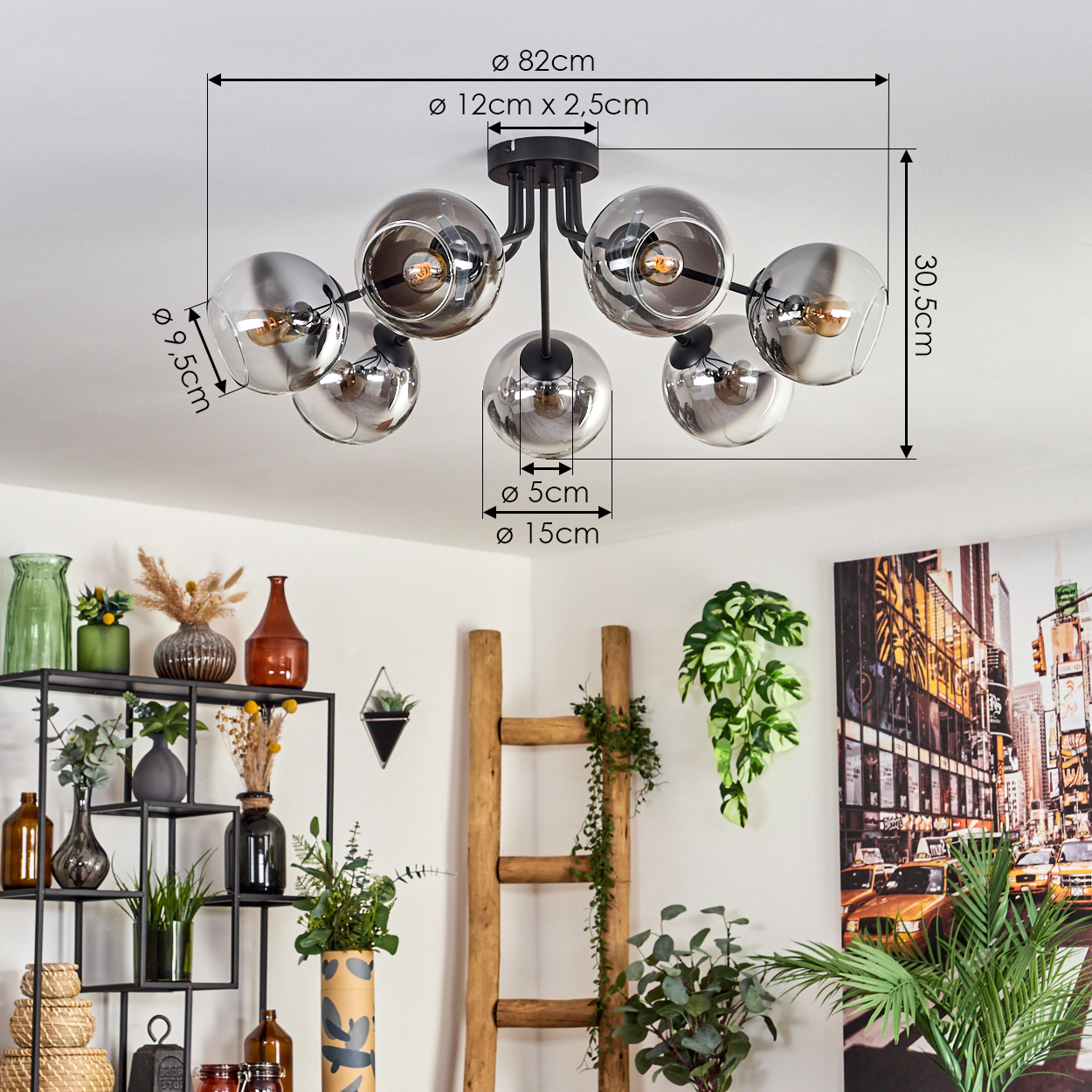 Eine Deckenlampe mit mehreren verchromten Kugeln und Lichtern, mit angegebenen Abmessungen. Innenraum mit Pflanzen und Dekor.