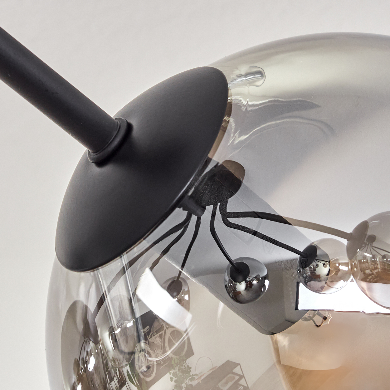 Nahaufnahme einer modernen Glaskugelleuchte. Schwarze Stäbe und eine Metallbasis befestigen sich an der Glaskugel.