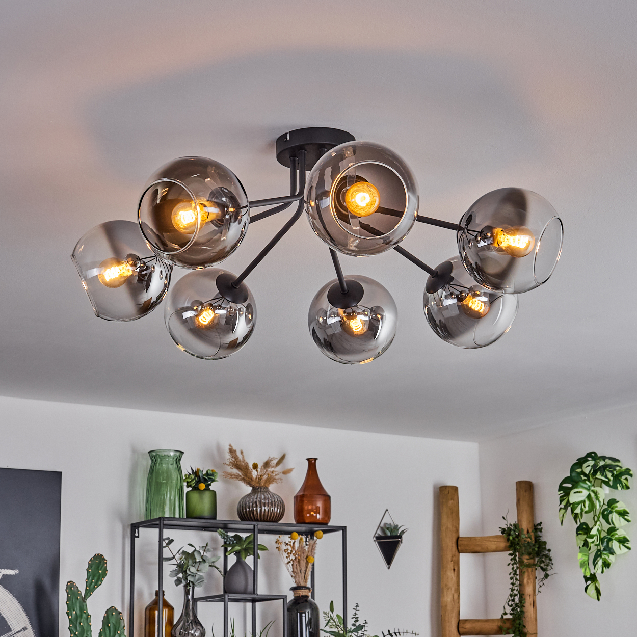 Eine moderne Deckenleuchte mit mehreren Glaskugeln, die Licht aussenden. Das Licht ist an einer weißen Decke montiert.