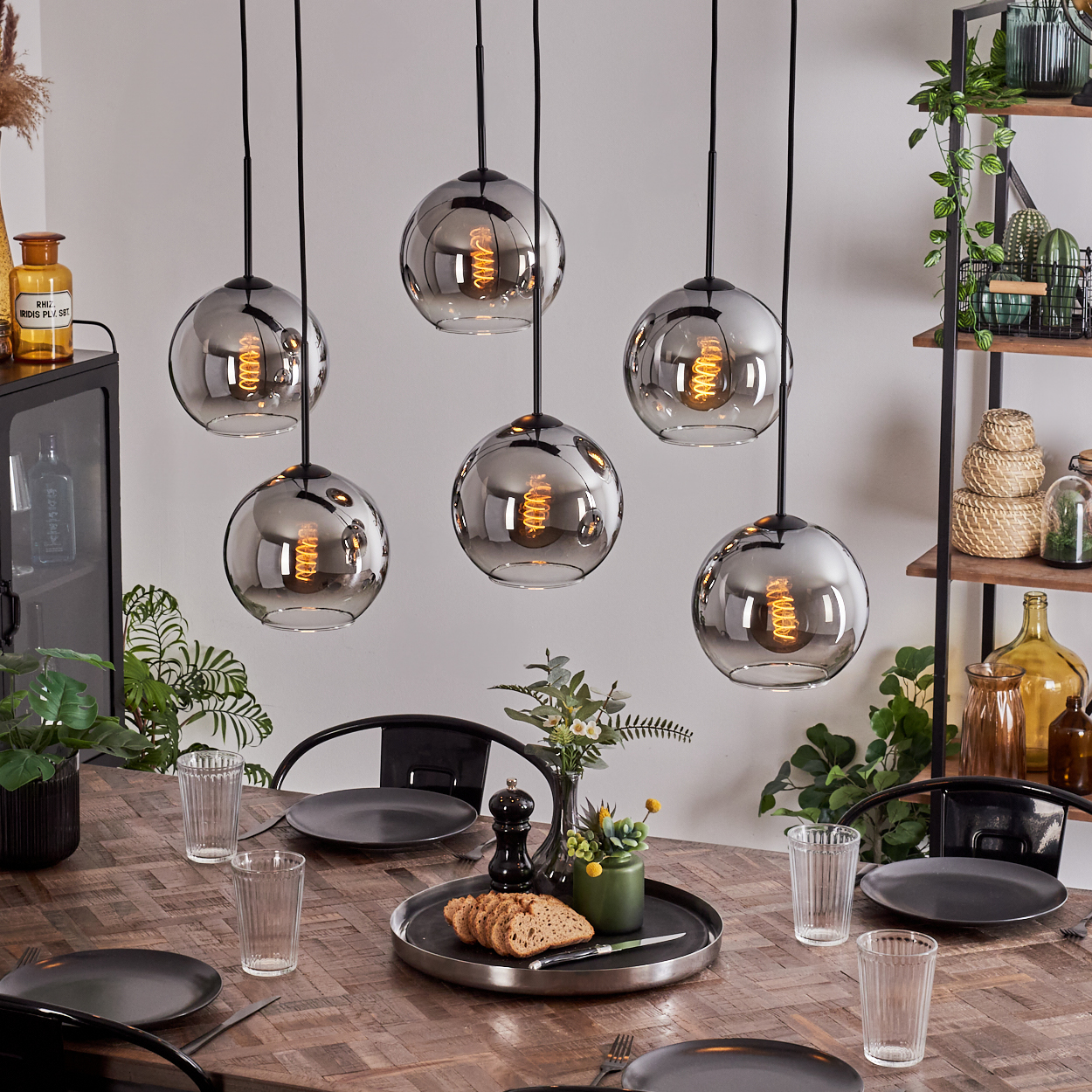 Sechs Pendelleuchten mit silbernen Kugeln hängen über einem Esstisch aus Holz, mit Esszimmer.