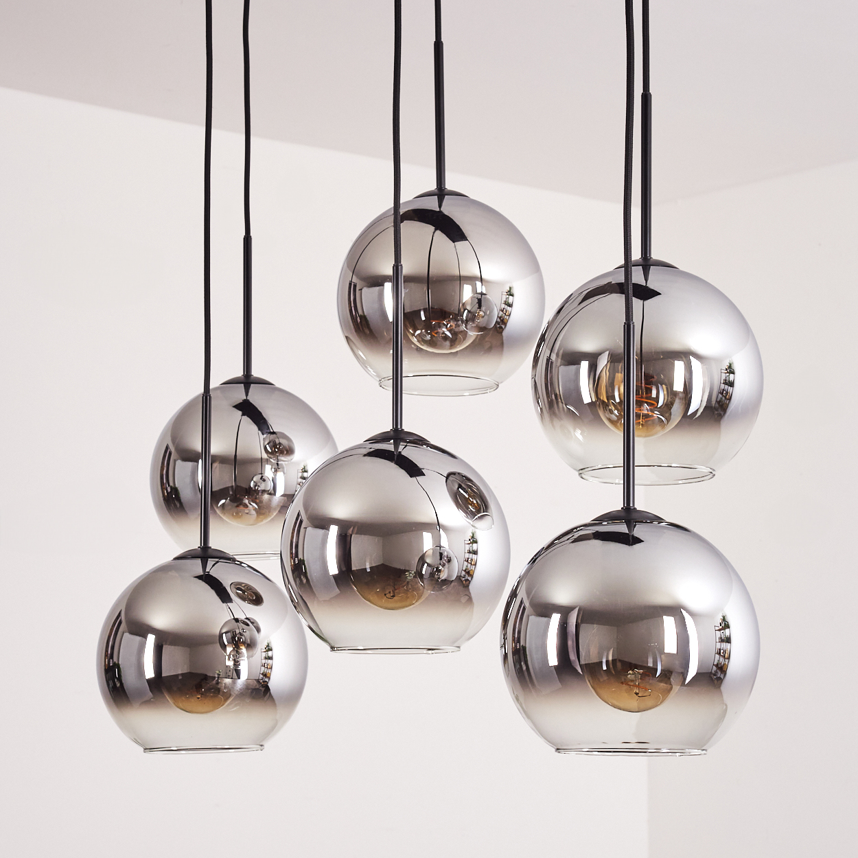 Sechs Pendelleuchten mit silbernen, reflektierenden Glaskugeln hängen von der Decke. Weißer Hintergrund.