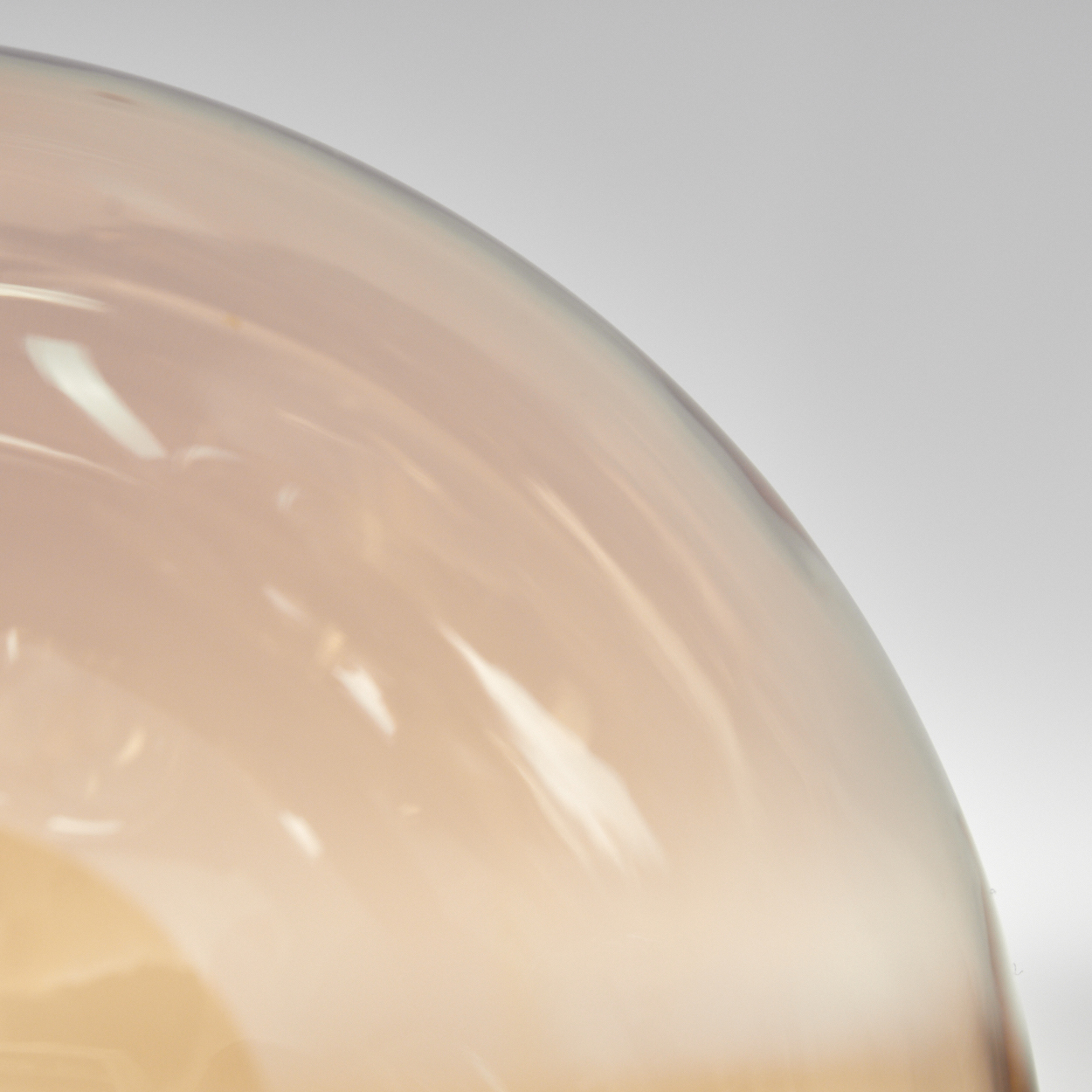 Nahaufnahme einer hellorangen Glaskugel. Die Oberfläche ist glatt und reflektierend, mit einem Gradienteneffekt.