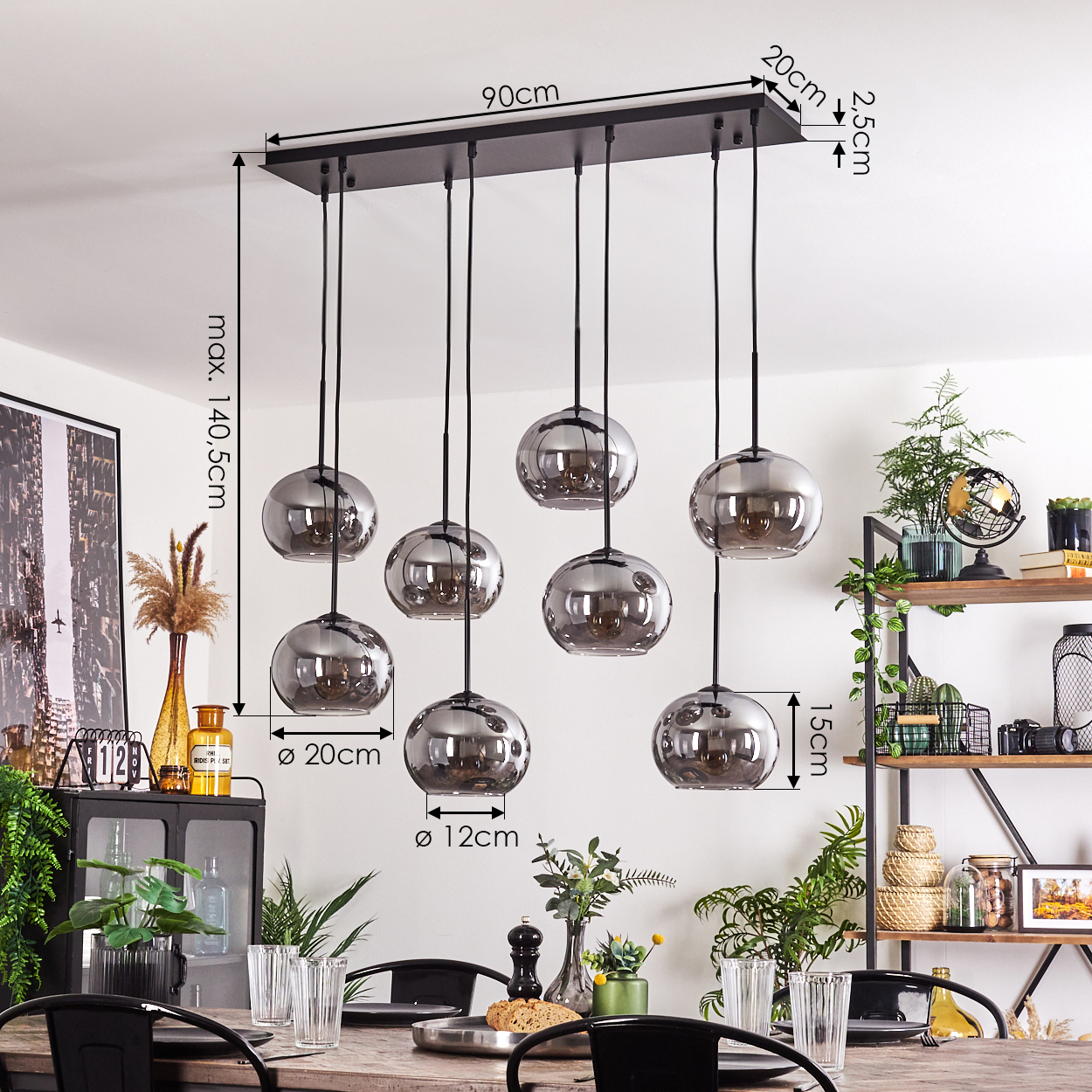 Esszimmer mit acht hängenden Kugelleuchten. Ein Holztisch mit Gläsern und Pflanzen im Bild.