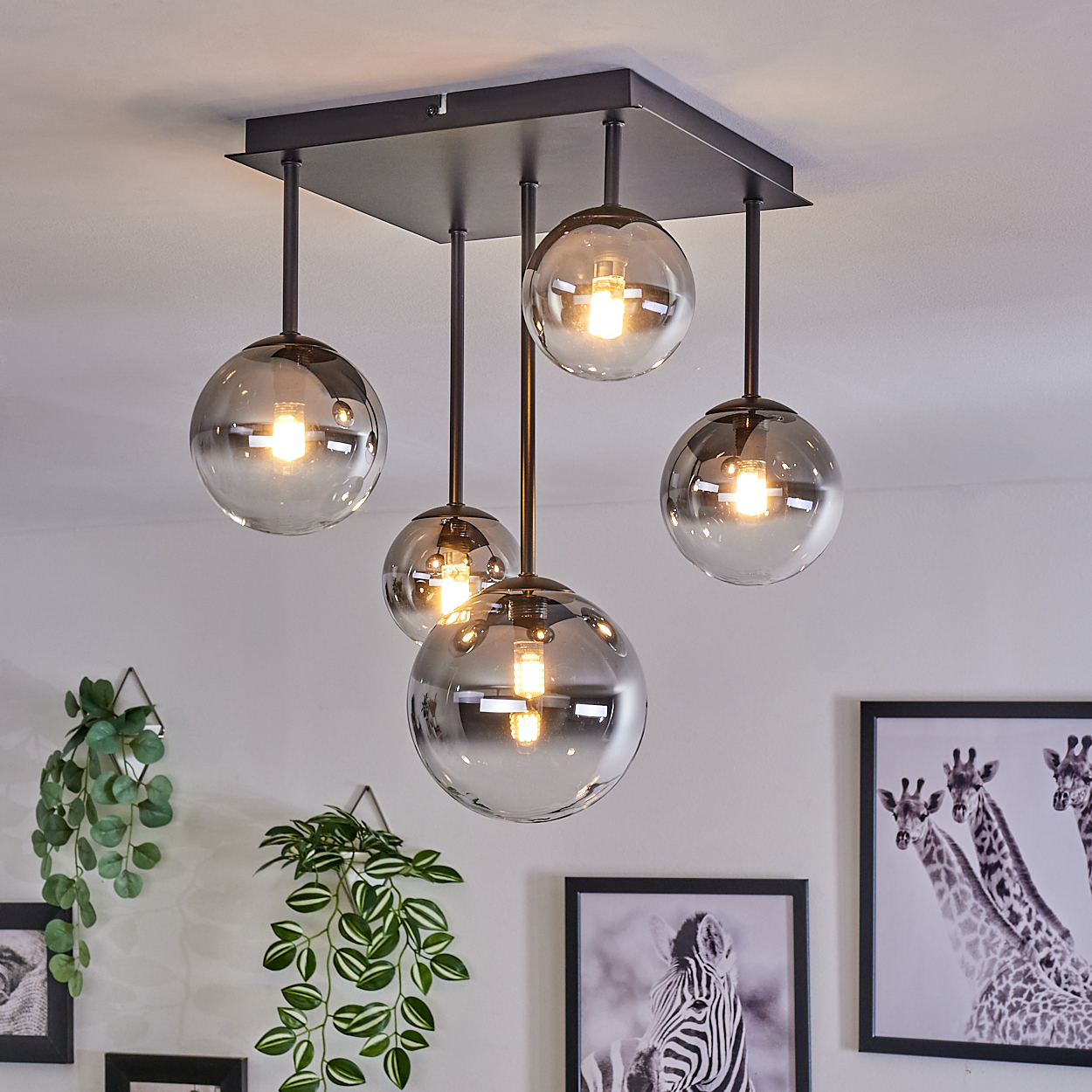 Eine Ansammlung von fünf Kugelleuchten, die von der Decke hängen. Die Lichter sind im Raum zentriert.