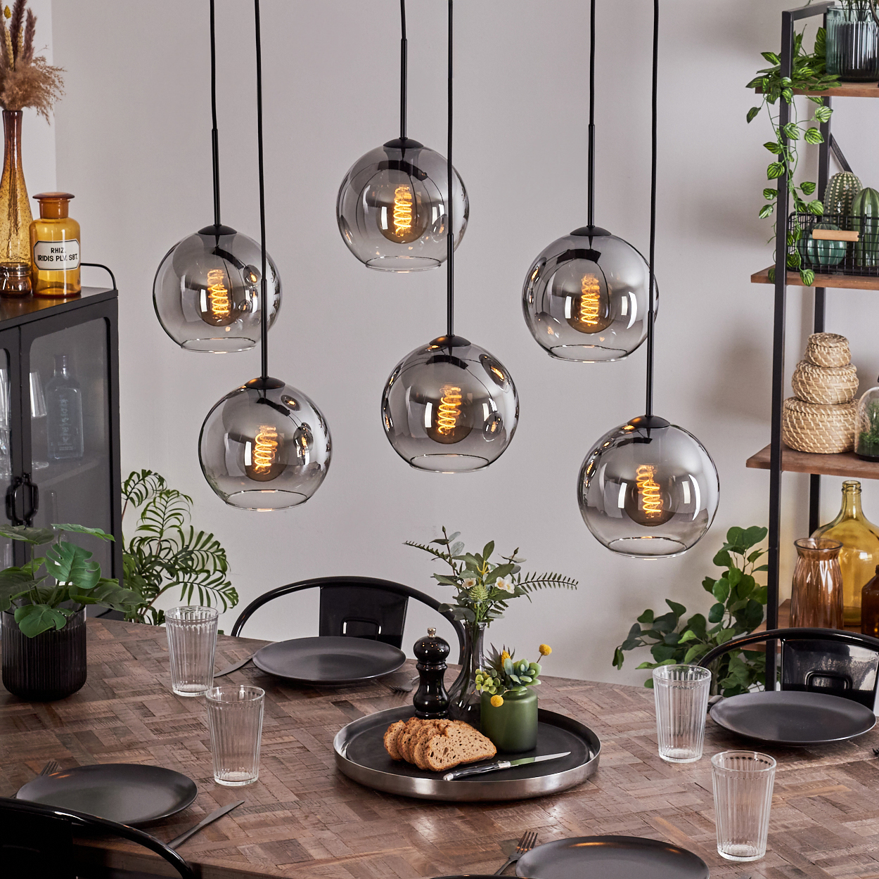 Ein Esszimmer mit sechs Pendelleuchten mit Glaskugeln, einem Holztisch und Dekorationsartikeln.