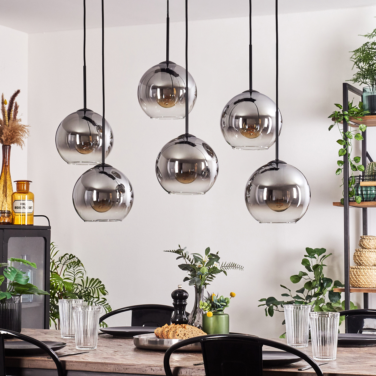 Ein Esszimmer mit sechs Pendelleuchten mit Glaskugeln, einem Holztisch und Dekorationsartikeln.