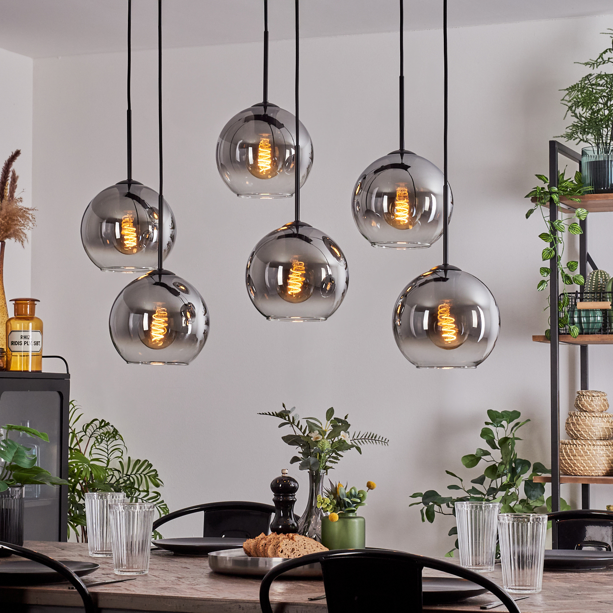 Ein Esszimmer mit sechs Pendelleuchten mit Glaskugeln, einem Holztisch und Dekorationsartikeln.