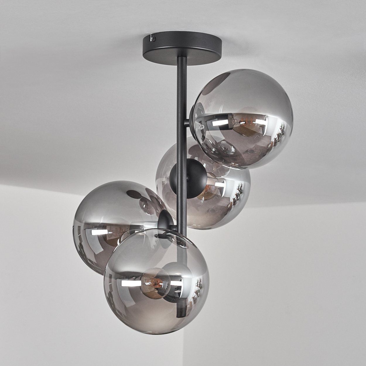 Deckenleuchte mit vier Glaskugeln. Die Kugeln sind transparent und reflektieren das Umgebungslicht.