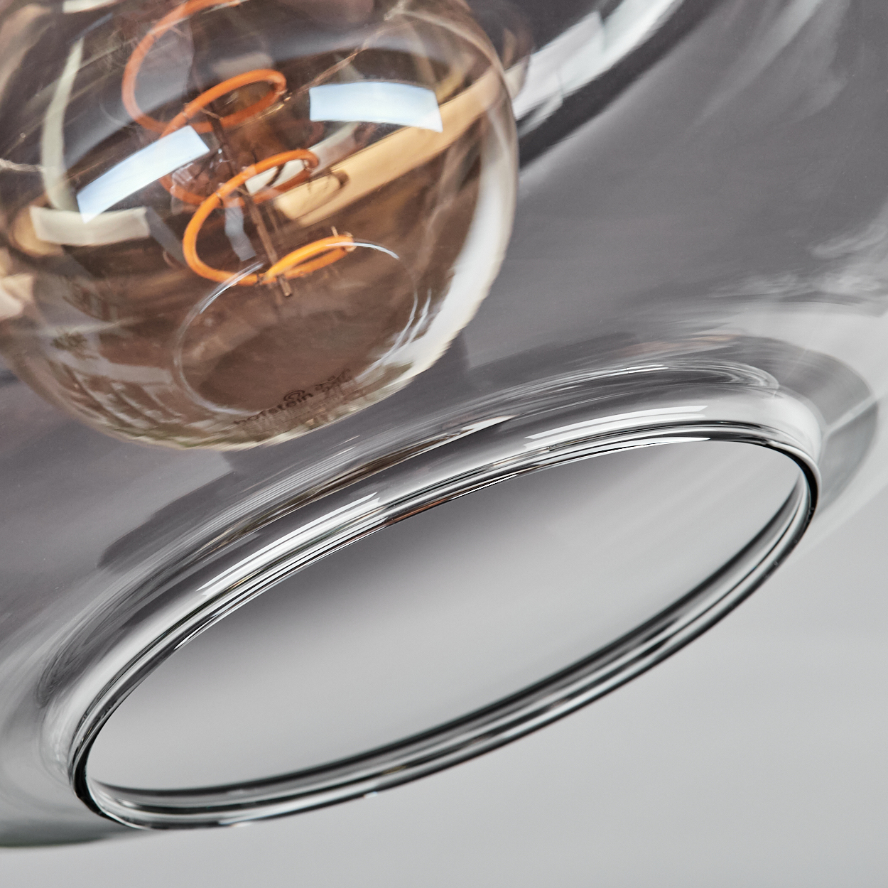 Nahaufnahme einer Glühbirne in einer grauen Glas-Deckenleuchte.