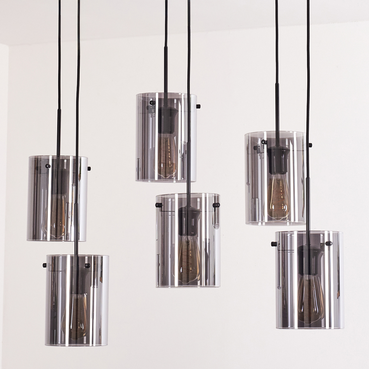 Sechs zylindrische Glasleuchten hängen von der Decke. Die Glühbirnen sind sichtbar.