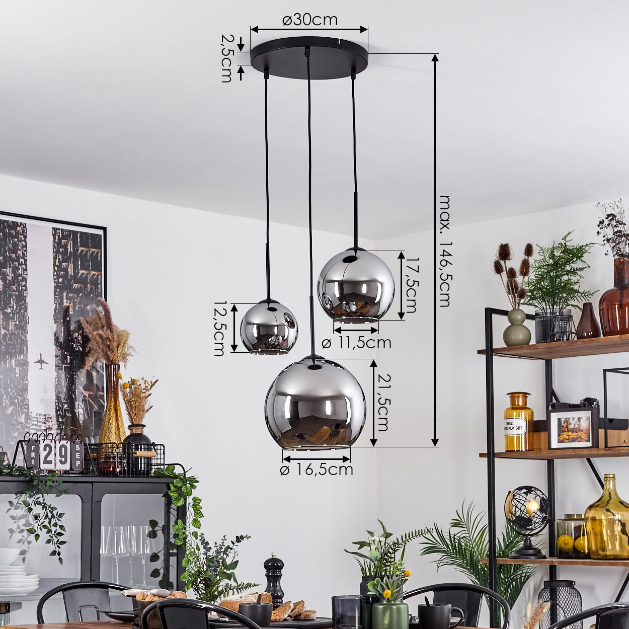 Ein Esszimmer mit einer dreikugeligen Pendelleuchte. Die Kugeln sind silberfarben, mit angegebenen Abmessungen. Eine Tischdekoration ist sichtbar.