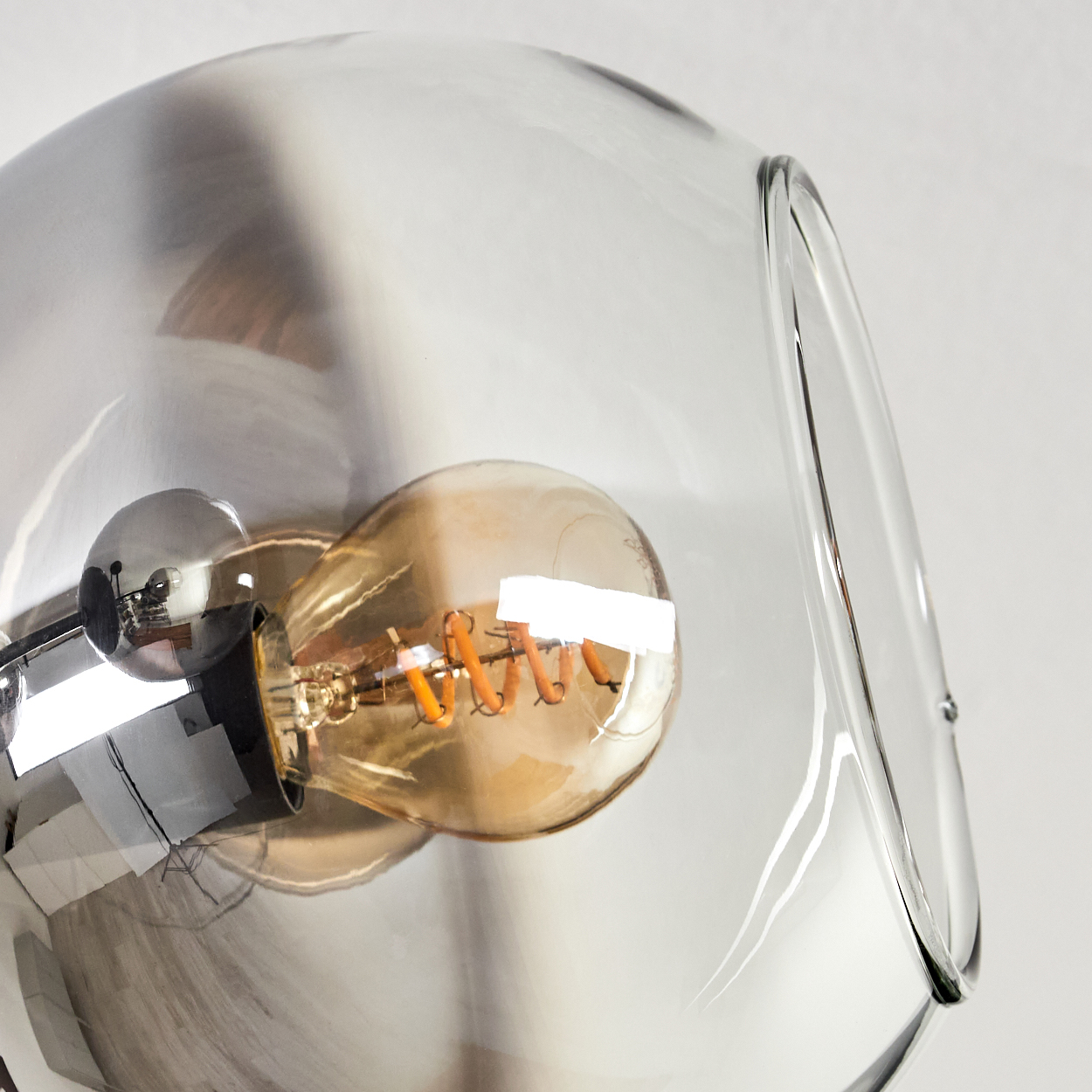 Nahaufnahme einer Glühbirne in einem durchsichtigen Globus. Der Globus ist Teil einer Deckenleuchte.