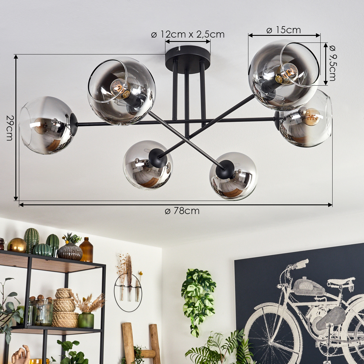 Ein Esszimmer mit einer Deckenlampe. Sechs silberne Kugeln befinden sich auf schwarzen Stäben, mit den angegebenen Abmessungen. Pflanzen sind sichtbar.