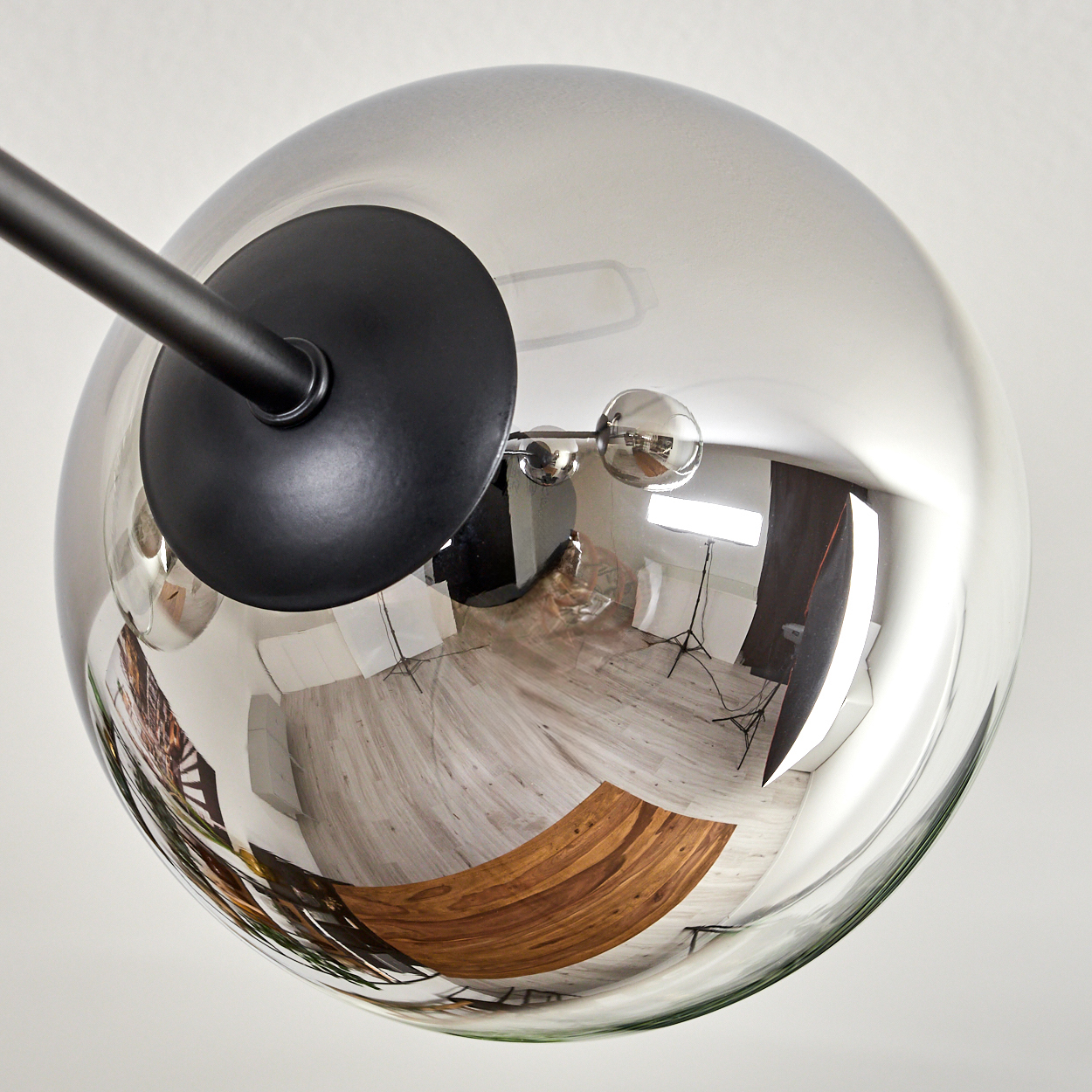 Reflektierende Glaskugellampe reflektiert Raum mit Möbeln. Lampe an schwarzem Stab.