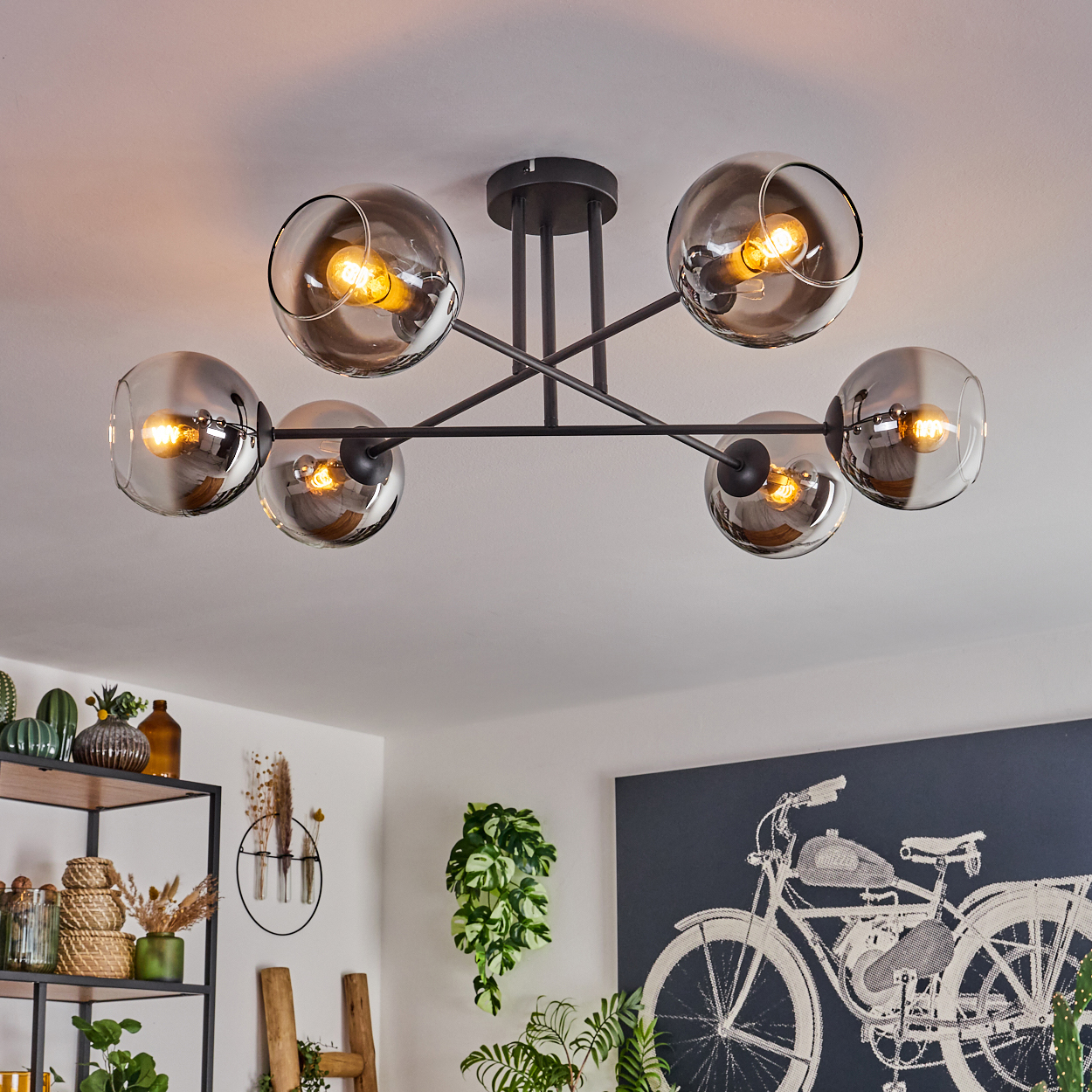 Eine Deckenleuchte mit sechs verspiegelten Kugelschirmen. Die Lampen haben sichtbare Glühbirnen und befinden sich in einem Raum.