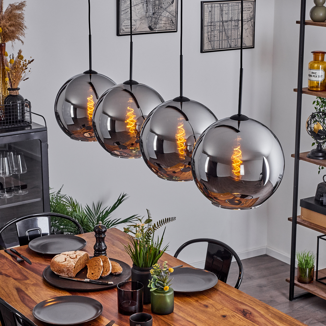 Esszimmer mit Holztisch und vier Glaskugellampen. Essen und Dekoration sind vorhanden.