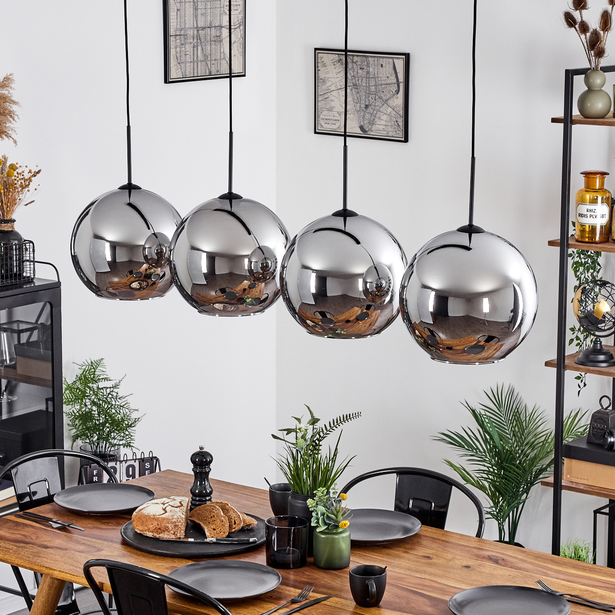 Esszimmer mit Holztisch und vier Glaskugellampen. Tisch mit Essen und Deko gedeckt.