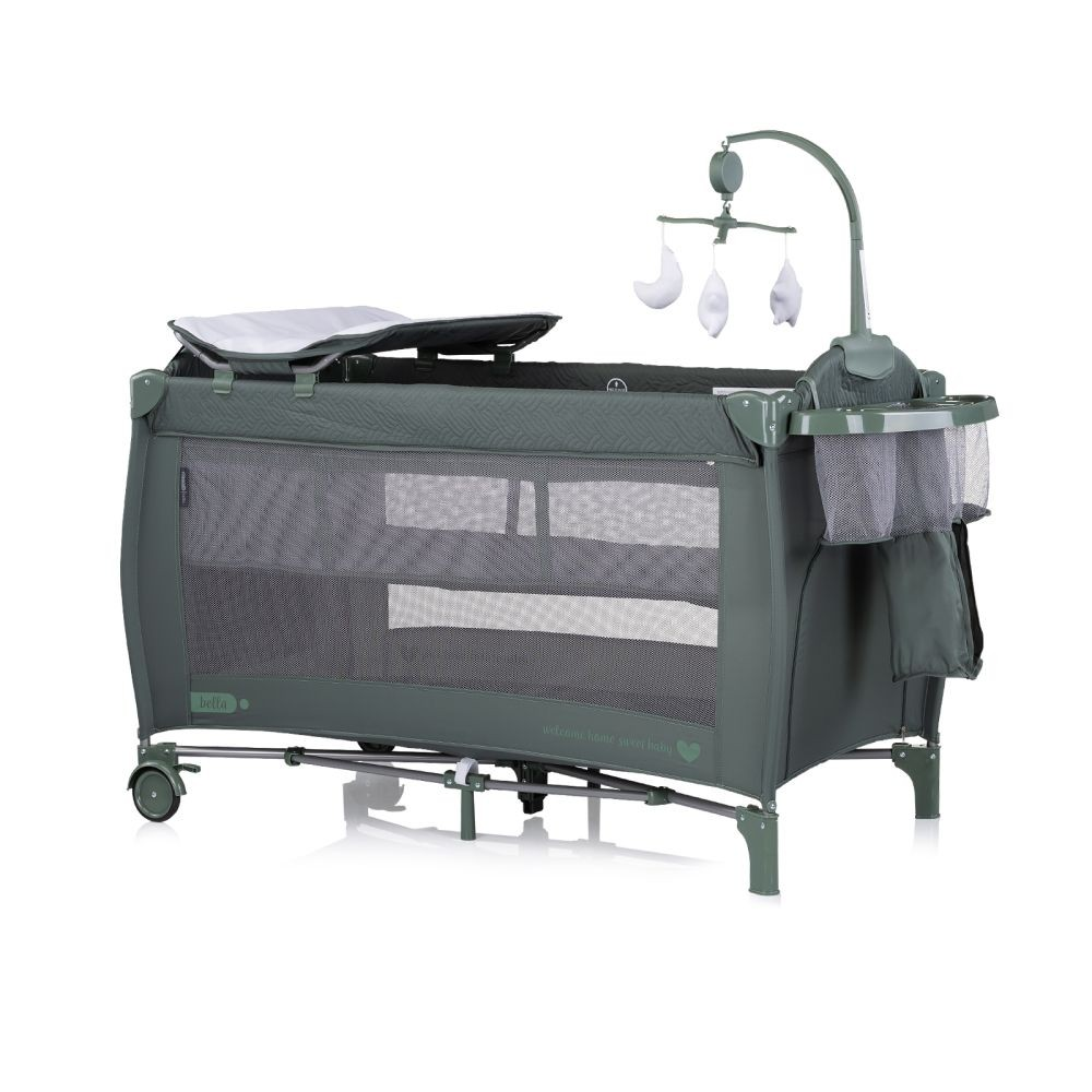 Ein grüner Baby-Laufstall mit Wickeltisch und Mobile darüber.
