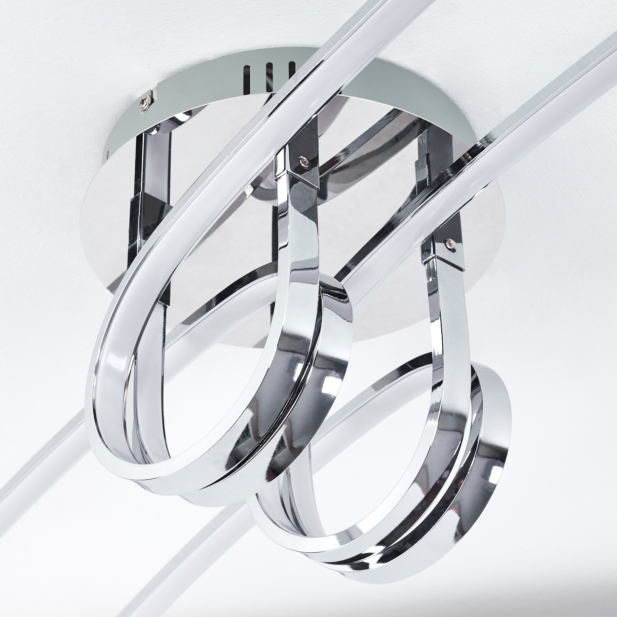 Chrome Deckenlampe mit Schlaufendesign, an weißer Decke montiert. Die Leuchte ist ausgeschaltet.