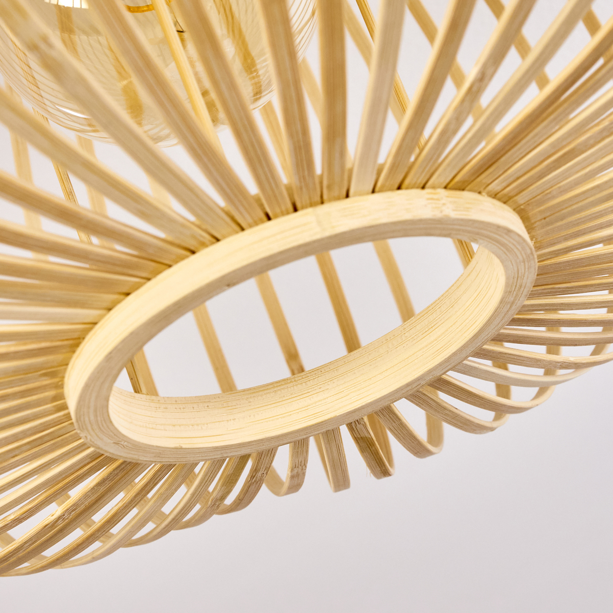 Nahaufnahme der Bambuslampe. Zeigt Details der Lampenstruktur und der Glühbirne.
