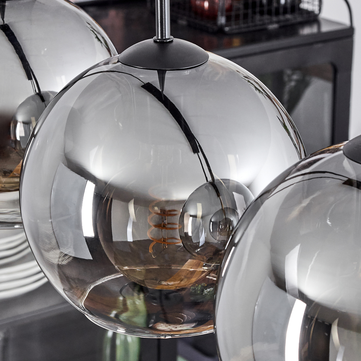 Nahaufnahme von drei kugelförmigen Leuchten mit reflektierender Oberfläche, die die Glühbirnen im Inneren zeigen.