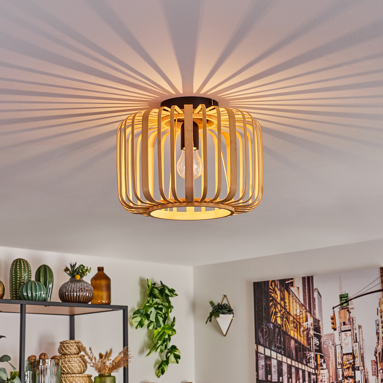 Eine Holz-Lamellen-Deckenleuchte, die Lichtmuster wirft. Der Raum ist mit Pflanzen und Kunst dekoriert.