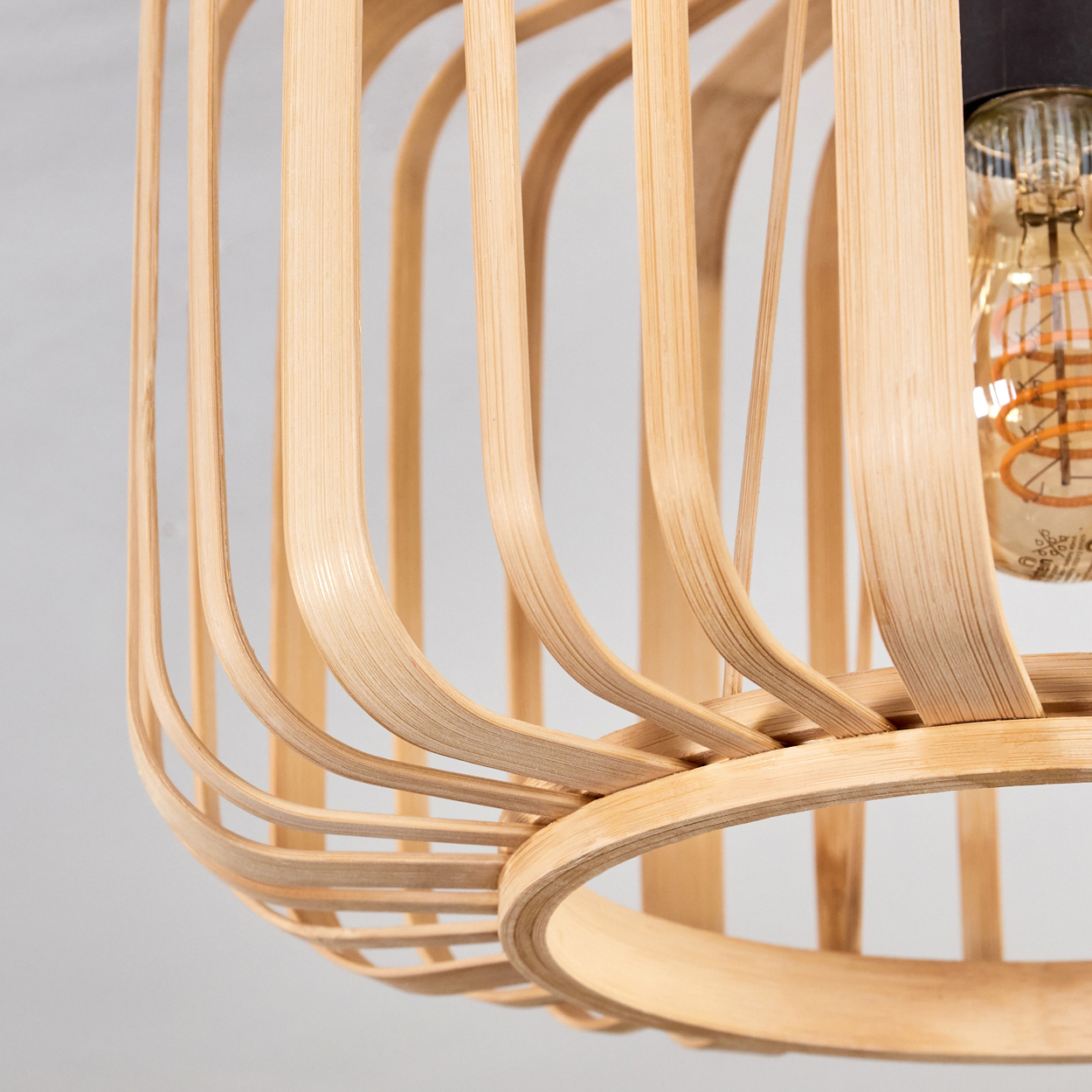 Nahaufnahme einer Holz-Lamellen-Deckenleuchte mit einer Edison-Glühbirne. Fokus auf die Details der Leuchte.