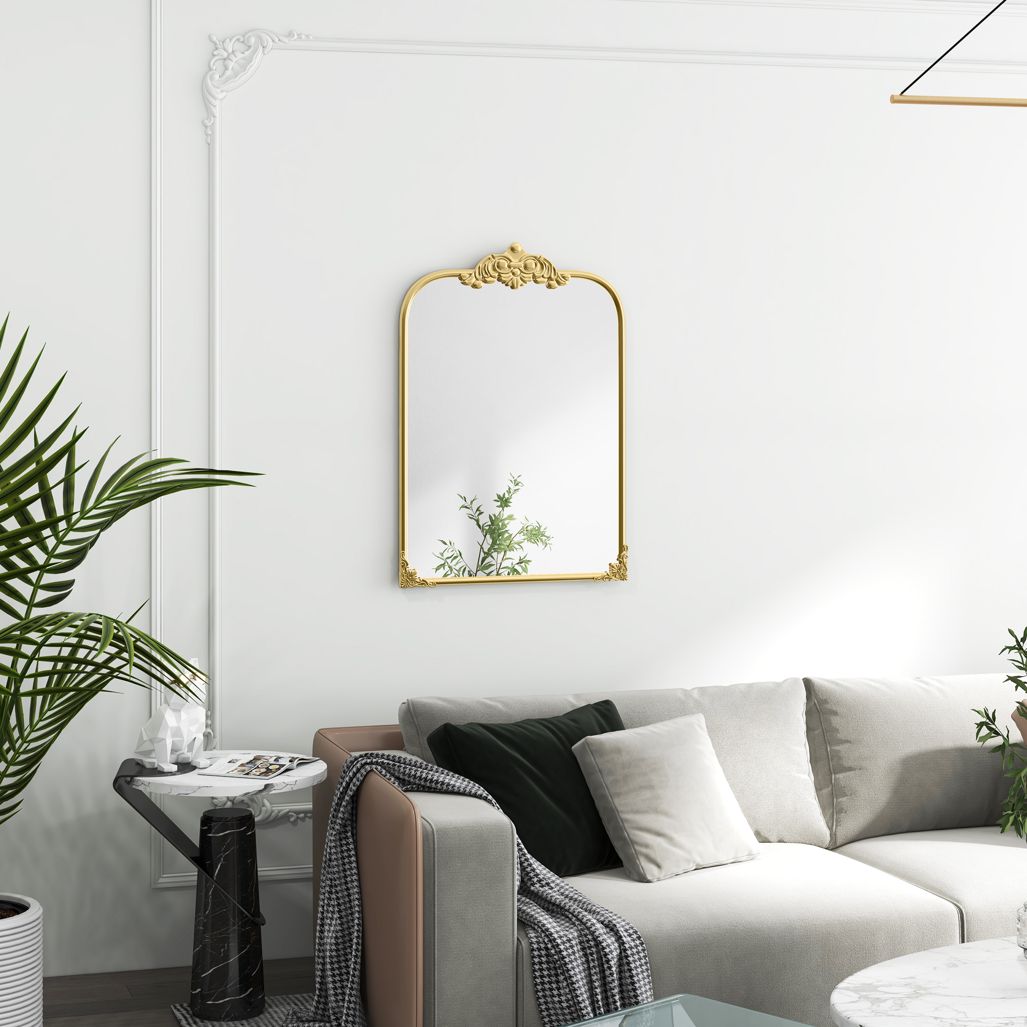 Goldgerahmter Spiegel mit dekorativer Spitze, an weißer Wand, Sofa und Tisch mit Pflanze sichtbar.