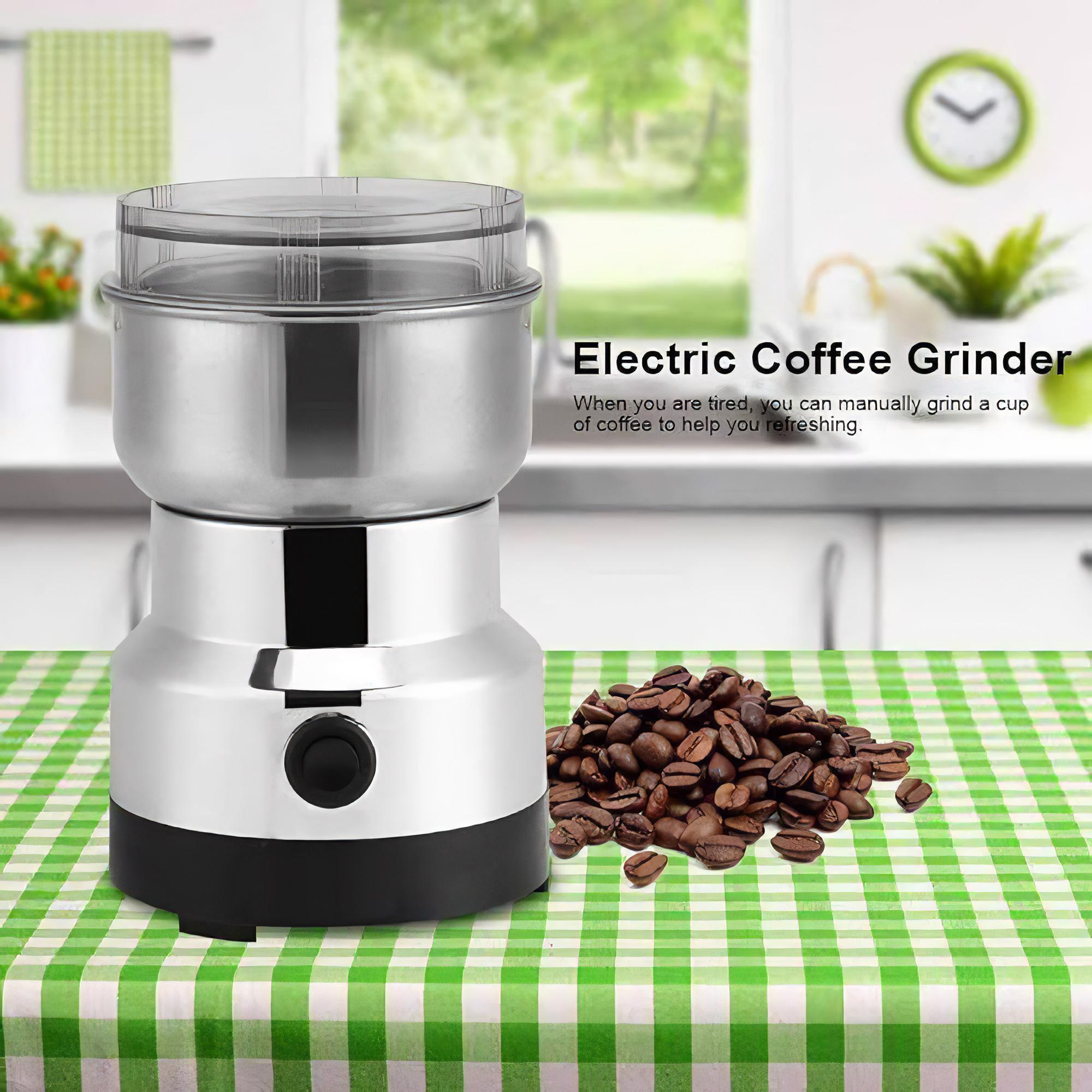 Elektrische Kaffeemühle mit Kaffeebohnen auf grün karierter Oberfläche.