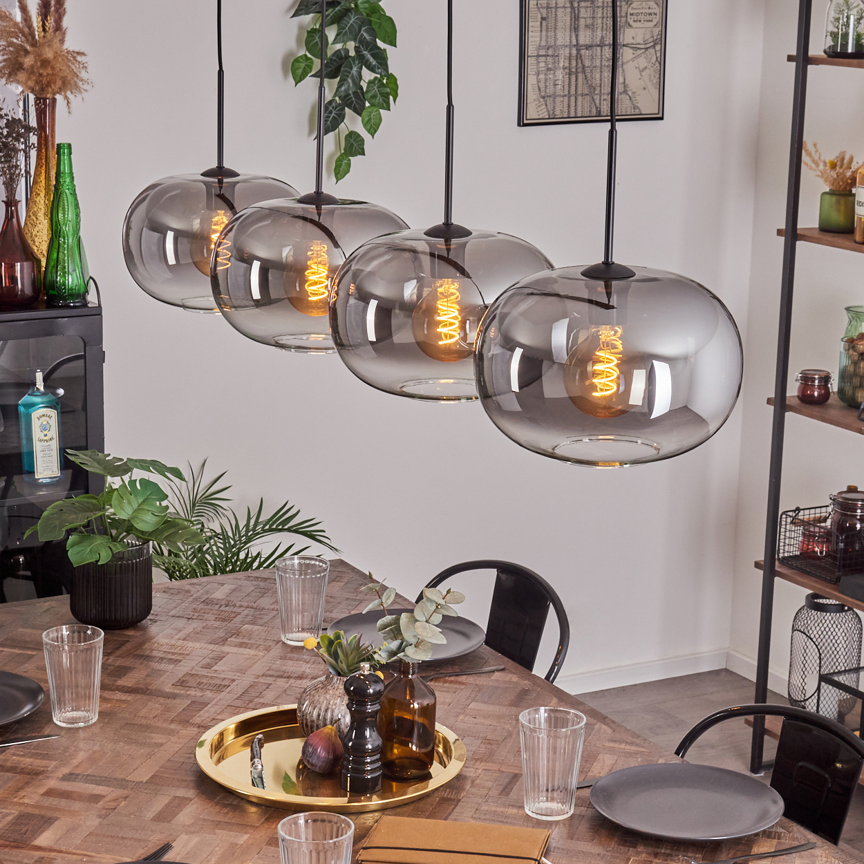 Ein Esszimmer mit einem Holztisch, Glashängeleuchten und dekorativen Elementen.