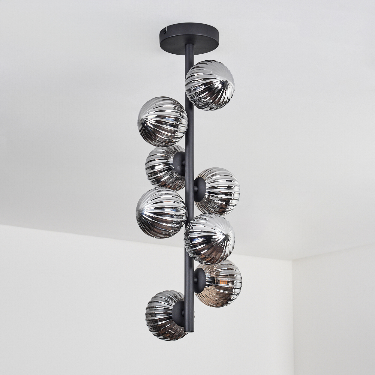 Eine schwarze Deckenlampe mit neun silbernen, geriffelten Kugeln, die an einer vertikalen Stange befestigt sind.