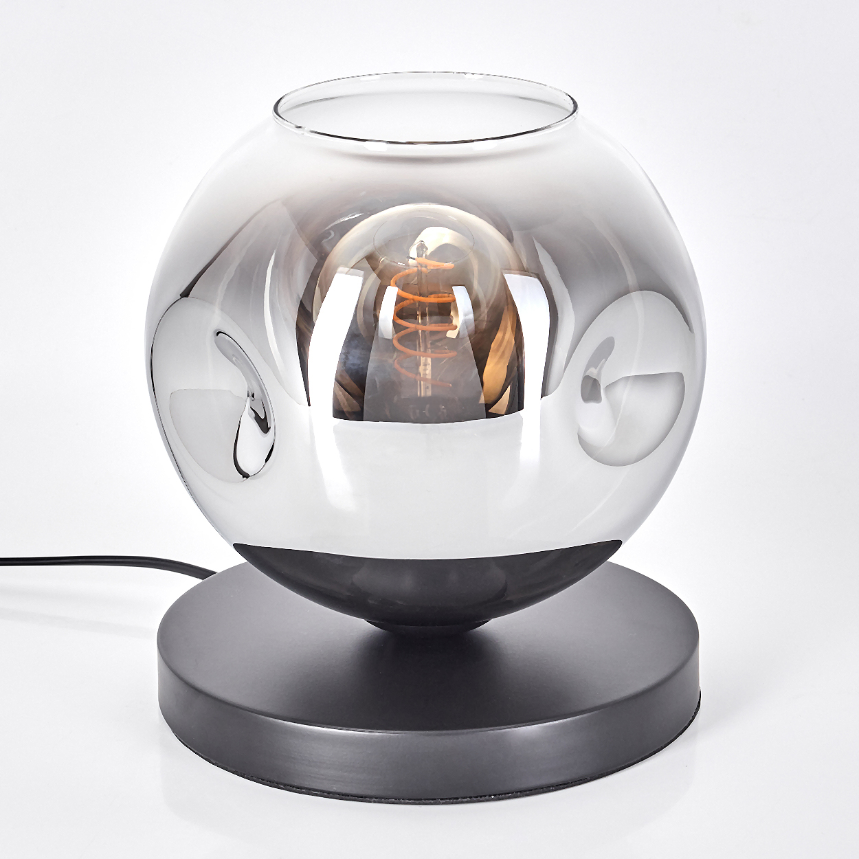 Eine Lampe mit Glaskugel-Schirm und Glühbirne, auf schwarzem Sockel. Weißer Hintergrund.