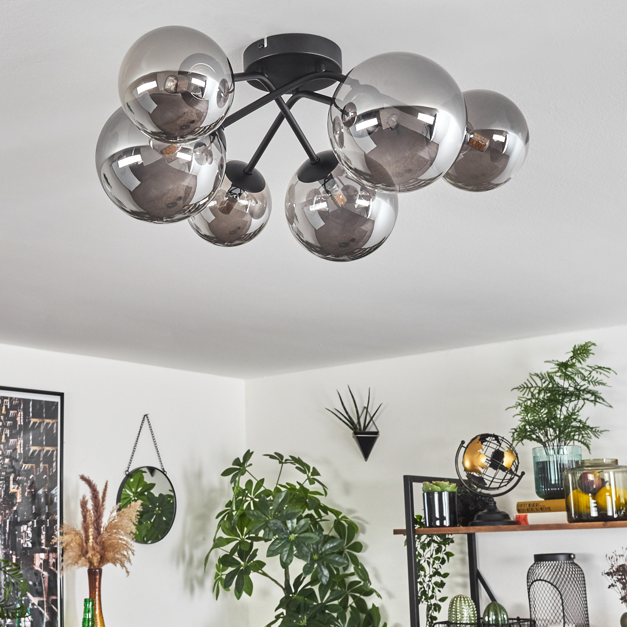 Eine Deckenleuchte mit sechs verspiegelten Glühlampen in einer mit Pflanzen dekorierten Wohnung.