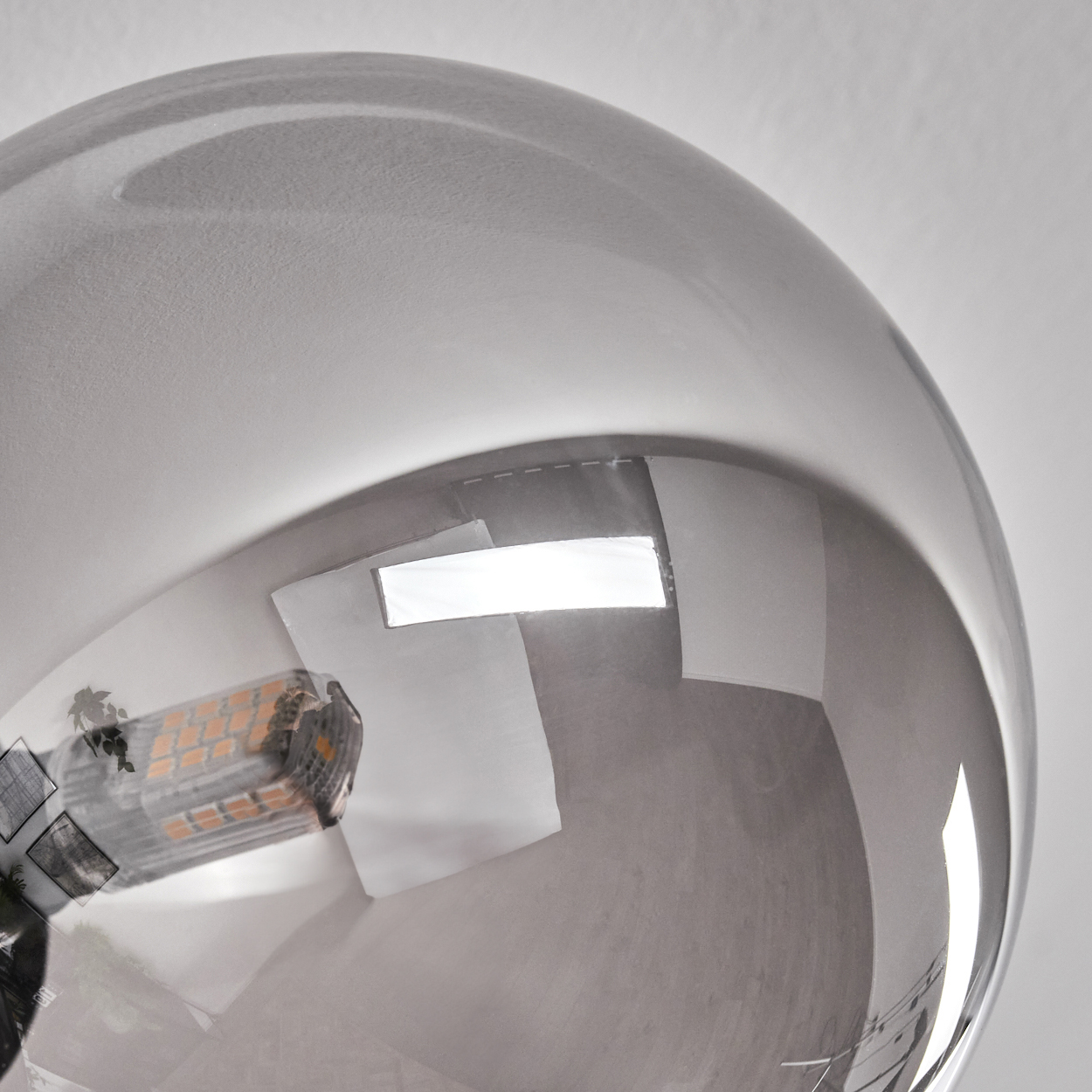 Nahaufnahme einer verspiegelten Glühbirne, die helles Licht und Innenelemente reflektiert.