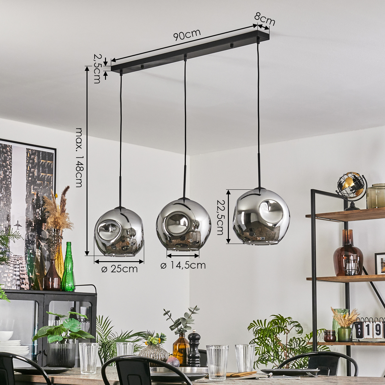 Drei chromartige kugelförmige Leuchten hängen mit Maßen. Der Hintergrund ist ein Esszimmer mit Tisch.