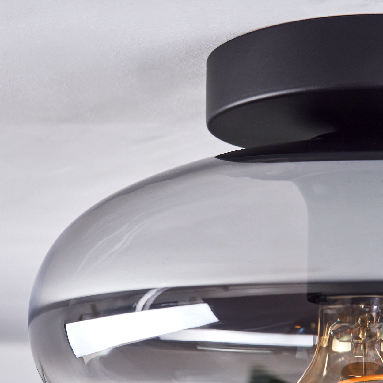 Nahaufnahme einer modernen Lampe. Der Schirm ist klar mit schwarzem Deckel, und eine Glühbirne ist sichtbar.