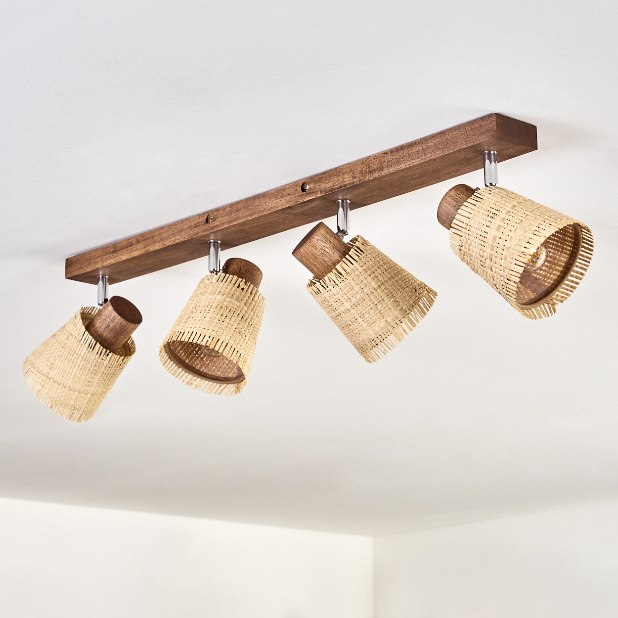 Vier Leuchten, die an einem Holzbalken befestigt sind. Jede Leuchte hat einen gewebten Schirm und eine Holzoberseite.