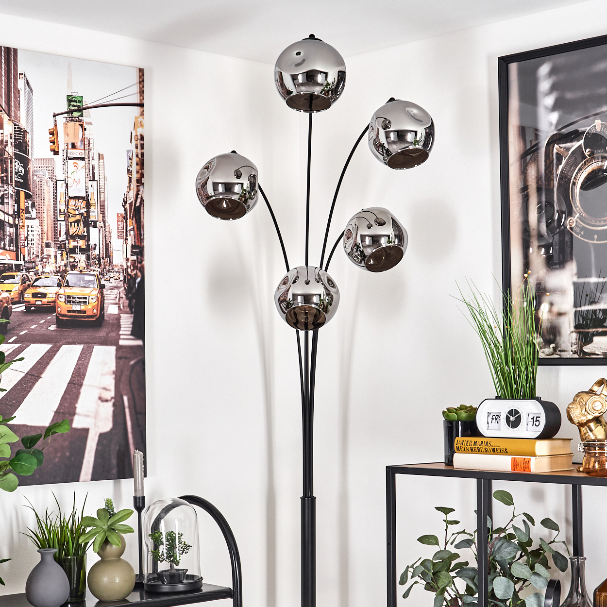 Eine Stehlampe in einer Ecke. Die Lampe hat fünf Chromkugeln. Im Hintergrund ist ein New York City Poster zu sehen.