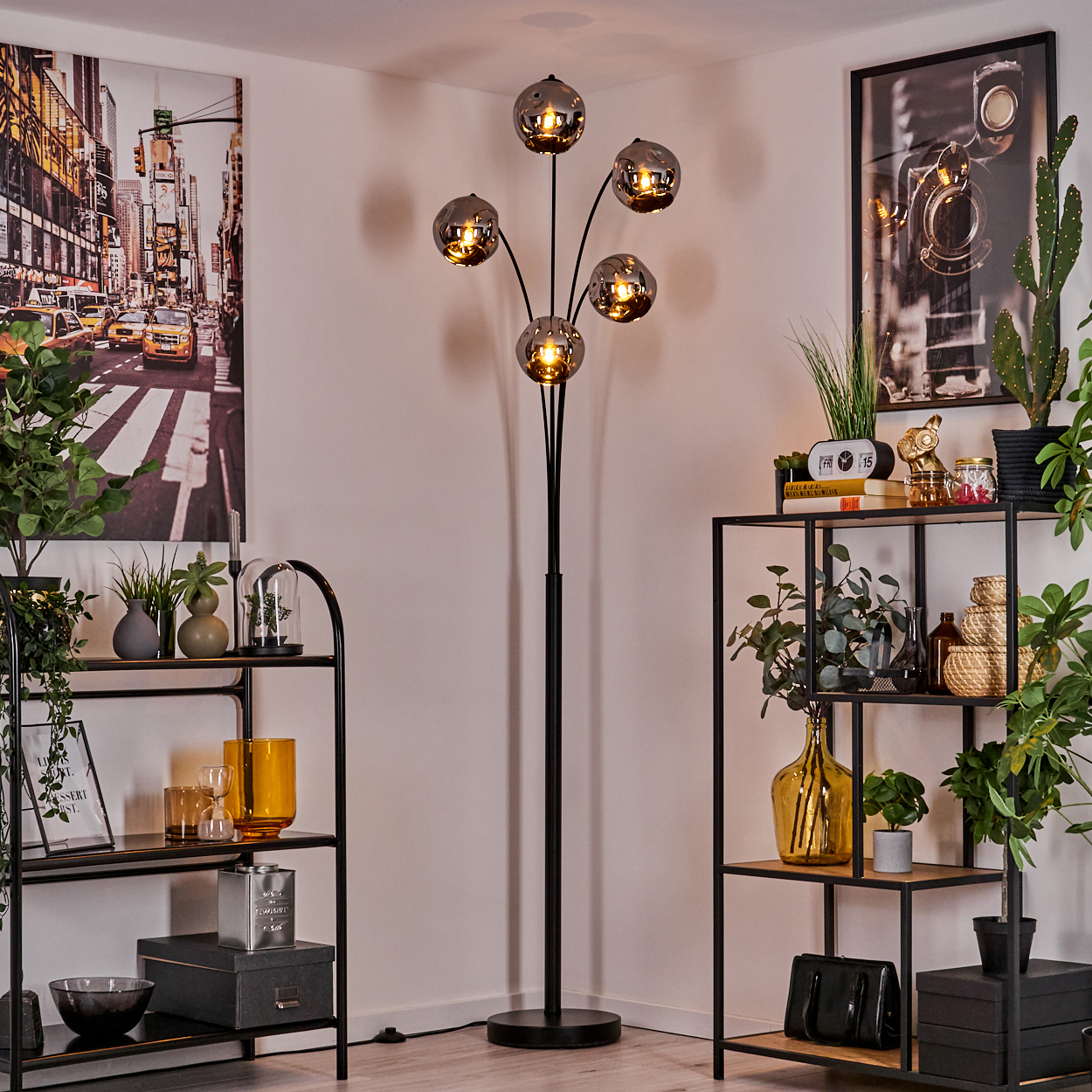 Eine Stehlampe mit fünf Chromkugel-Schirmen, in der Nähe von Regalen mit Dekorationen und einem Stadtbild-Kunstwerk.