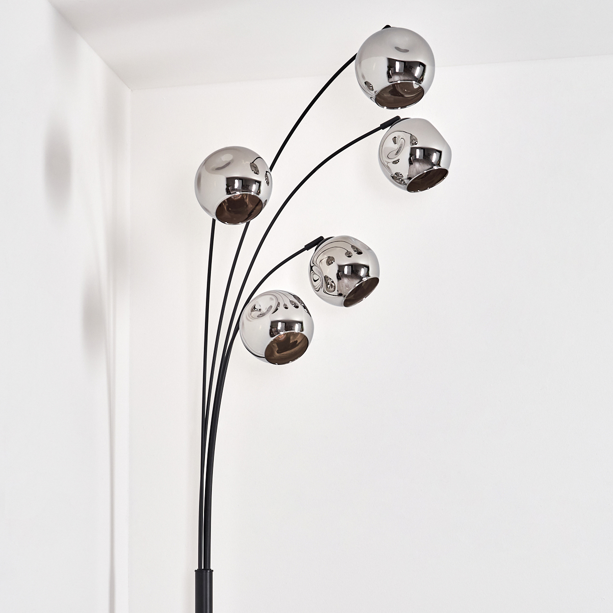 Eine Stehlampe mit mehreren Chromkugeln. Schwarze Stiele und ein schwarzer Sockel. Weißer Hintergrund.