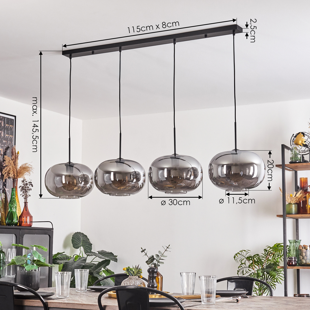 Vier Pendelleuchten mit silbernen Glaskugelschirmen hängen über einem Tisch. Maße sind sichtbar. Hintergrund ist Deko.