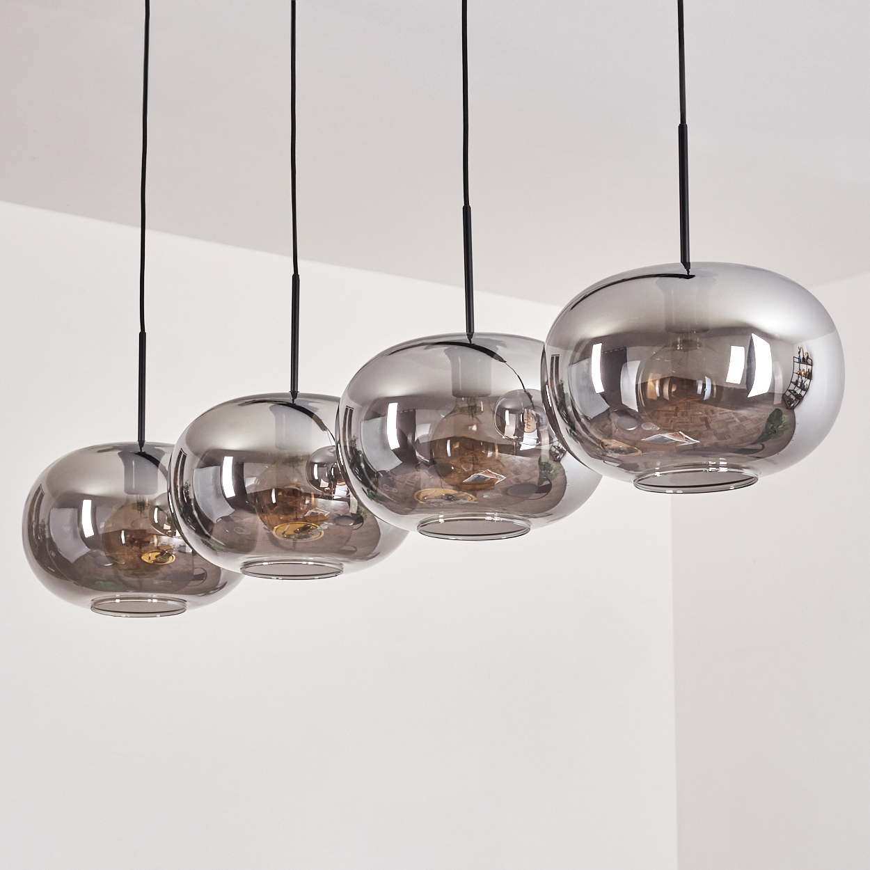 Vier Pendelleuchten aus Rauchglas hängen von der Decke, jede mit einer sichtbaren Glühbirne im Inneren.
