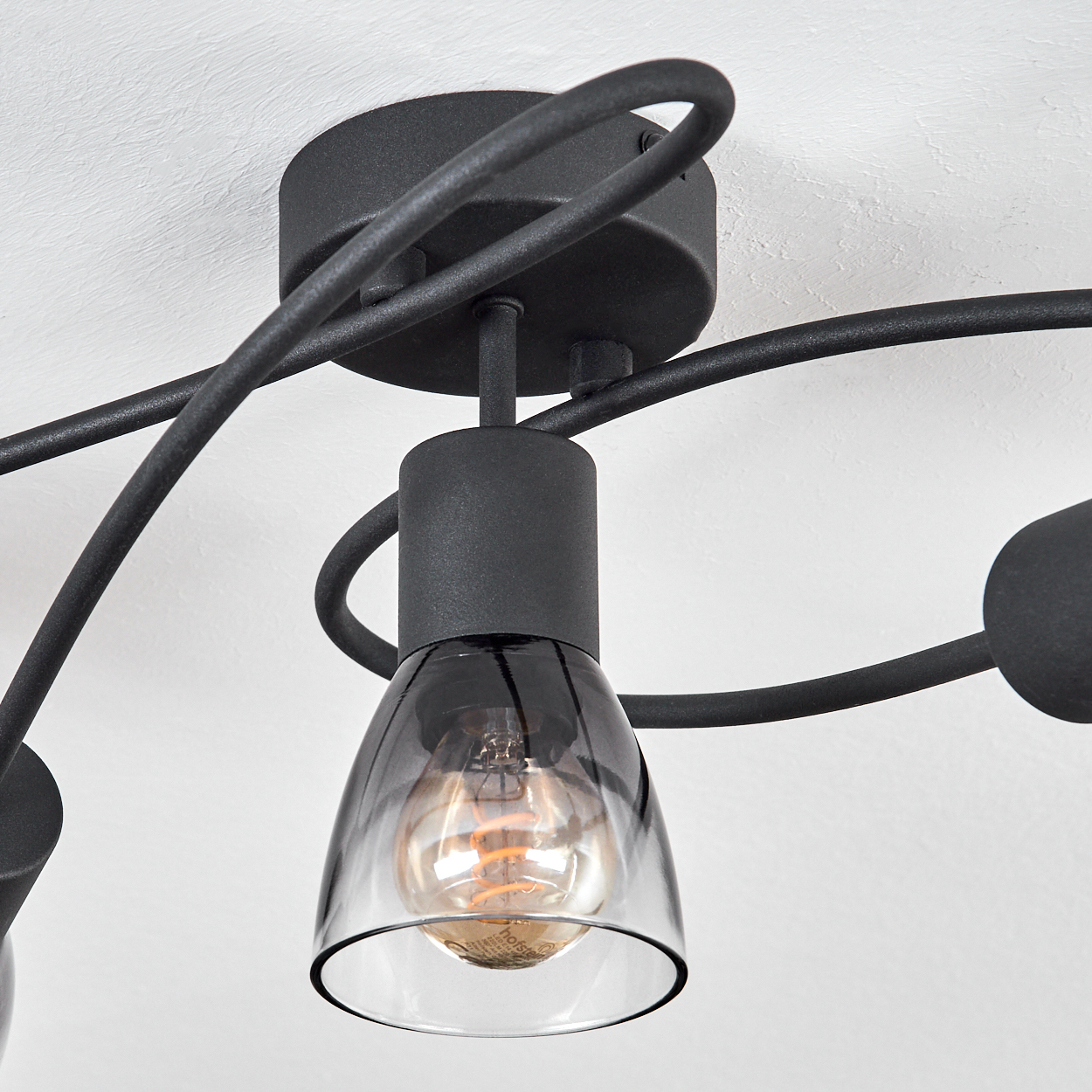 Nahaufnahme einer Deckenlampe mit schwarzem Rahmen und einer transparenten Glühbirne.
