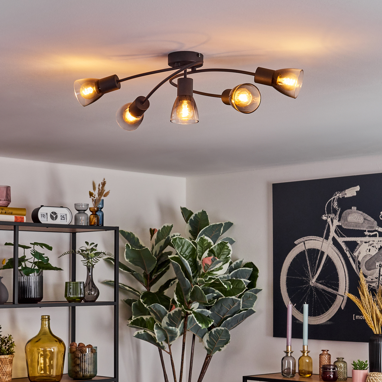 Deckenlampe mit sechs Lichtern, jeweils mit transparenter Glühbirne, in einem Raum mit Dekoration.